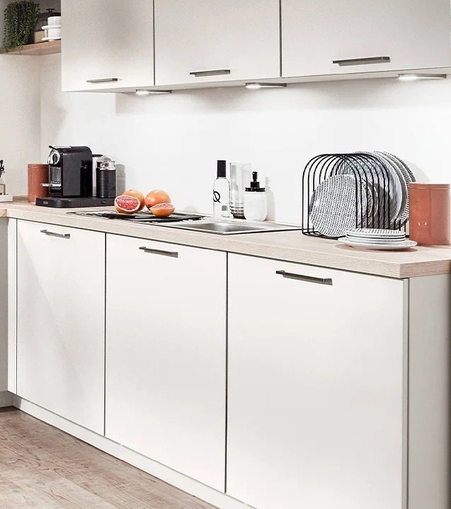 Spülzeile der Nobilia Moderne L-Küche magnolia mit Oberschränken und Unterbauleuchten